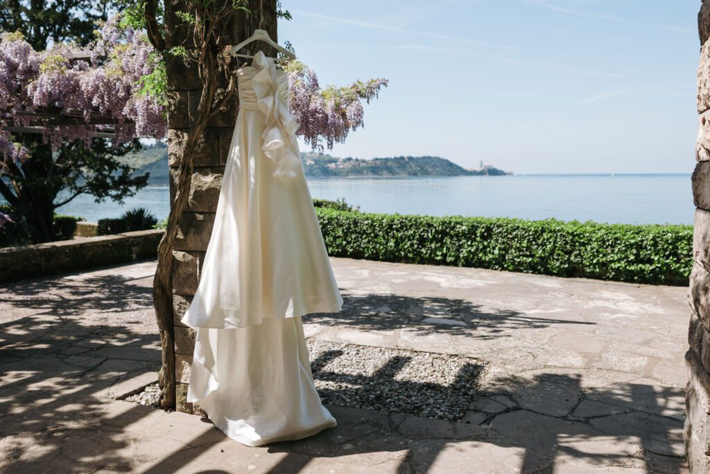 wedding dress hanging under blooming wisteria with sea view in Italy
