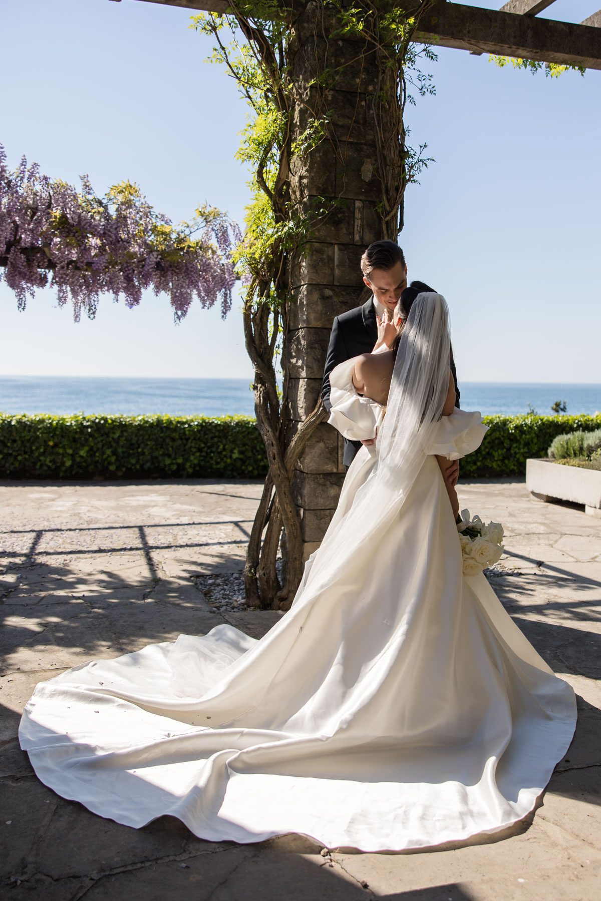 Romantic wedding portrait under blooming wisteria at Villa Tartini in Strunjan, Slovenia.