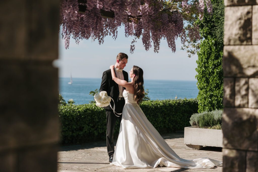 bride and groom embracing under wisteria pergola during destination wedding in Italy