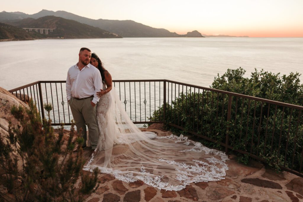 bride and groom in Cefalù Sicily with long veil overlooking the sea at golden hour
