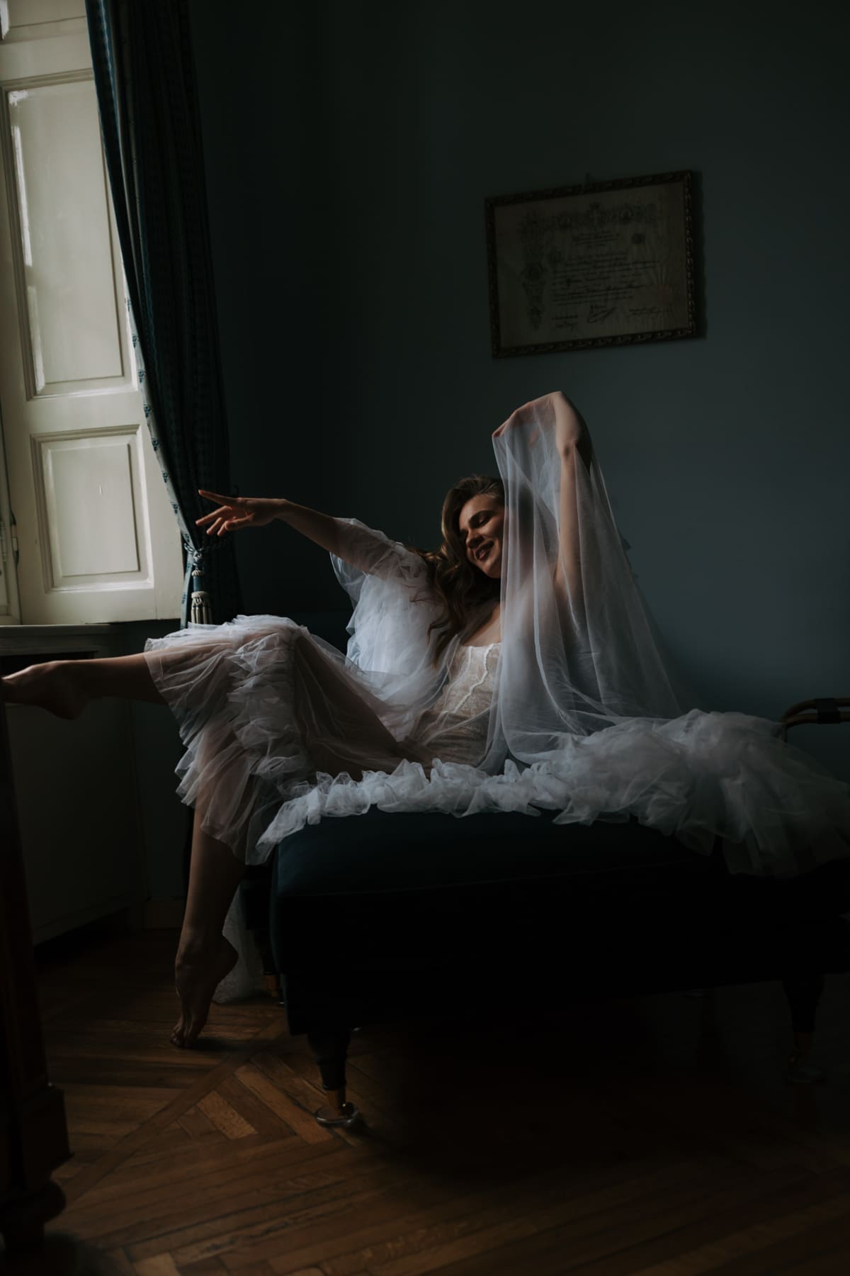 Bride in soft tulle dress getting ready by the window, intimate wedding morning moment with natural light in an Italian villa
