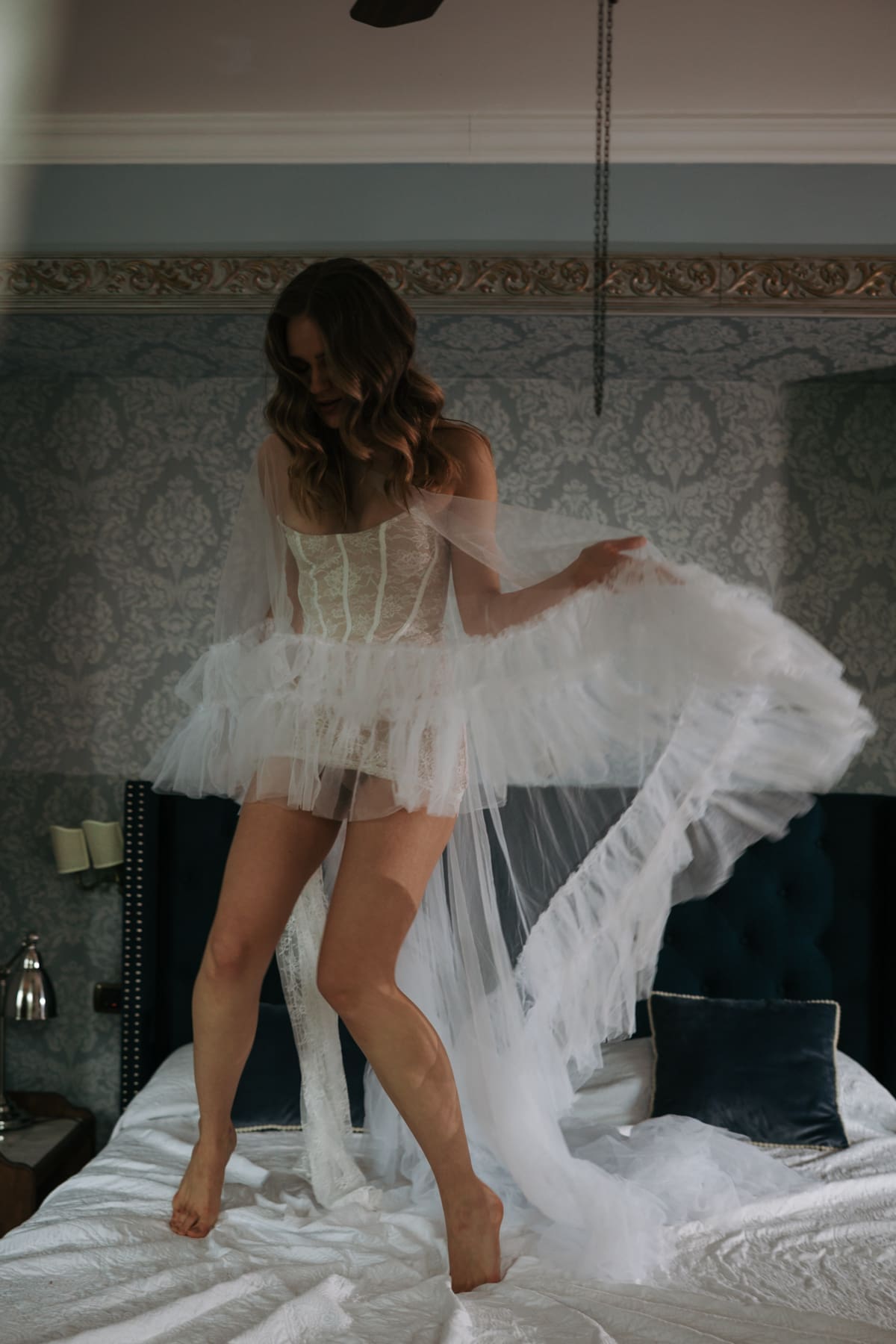 Bride jumping on a bed with flowing wedding dress, playful and intimate bridal morning moment in an elegant Italian villa