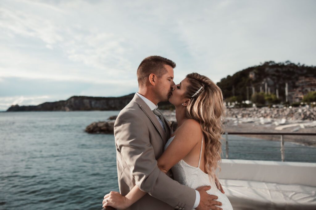 Romantic wedding couple kissing by the sea in Portopiccolo Italy during golden hour with soft coastal light
