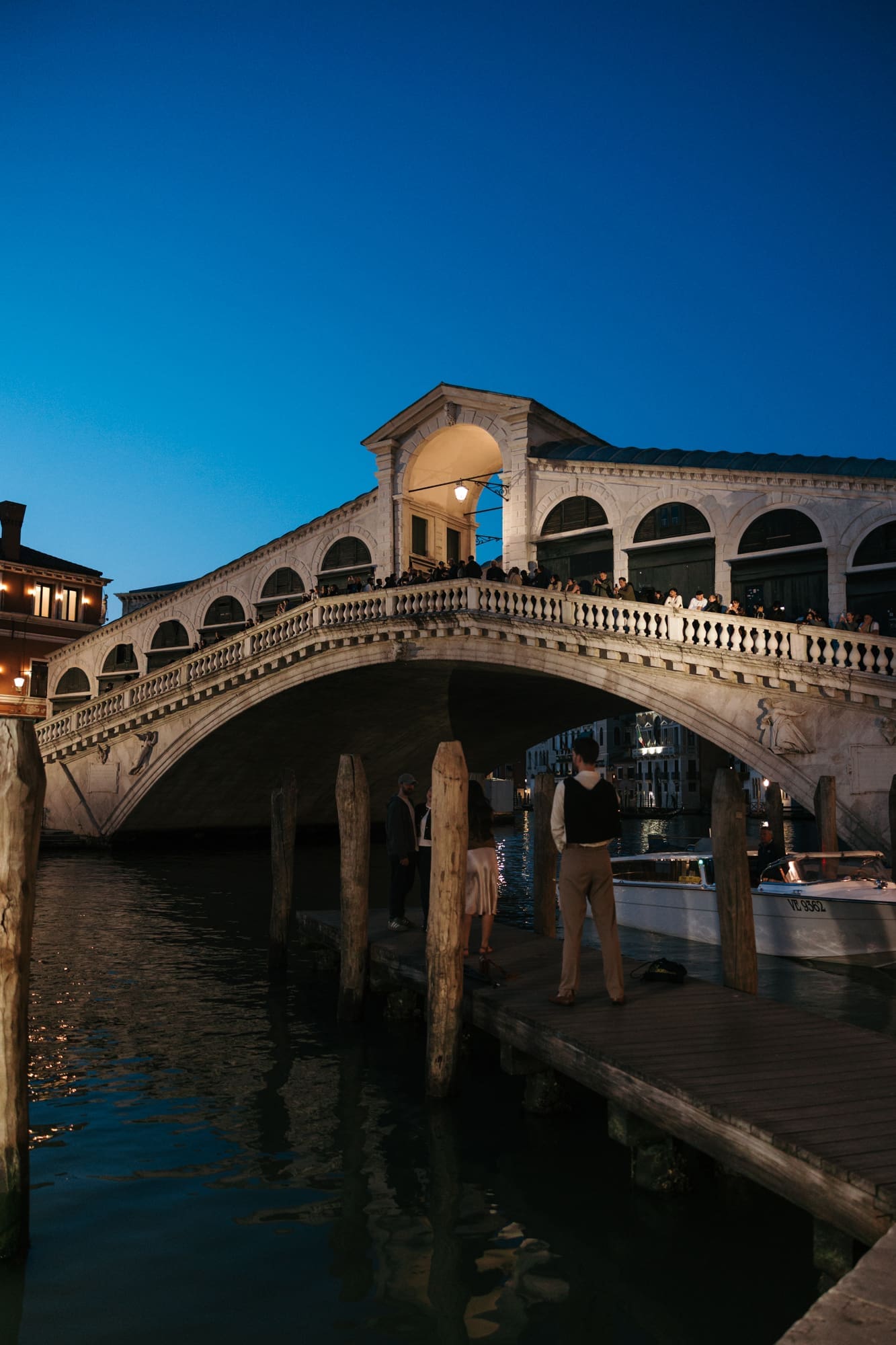 Romantic evening at Rialto Bridge in Venice with historic architecture, gondola docks, and blue hour light over the Grand Canal in Italy.
