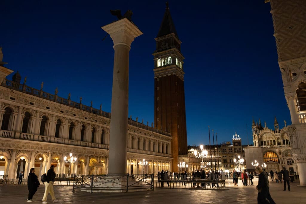 Evening view of Piazza San Marco in Venice with St Mark’s Campanile and glowing historic architecture, romantic blue hour atmosphere in Italy.
