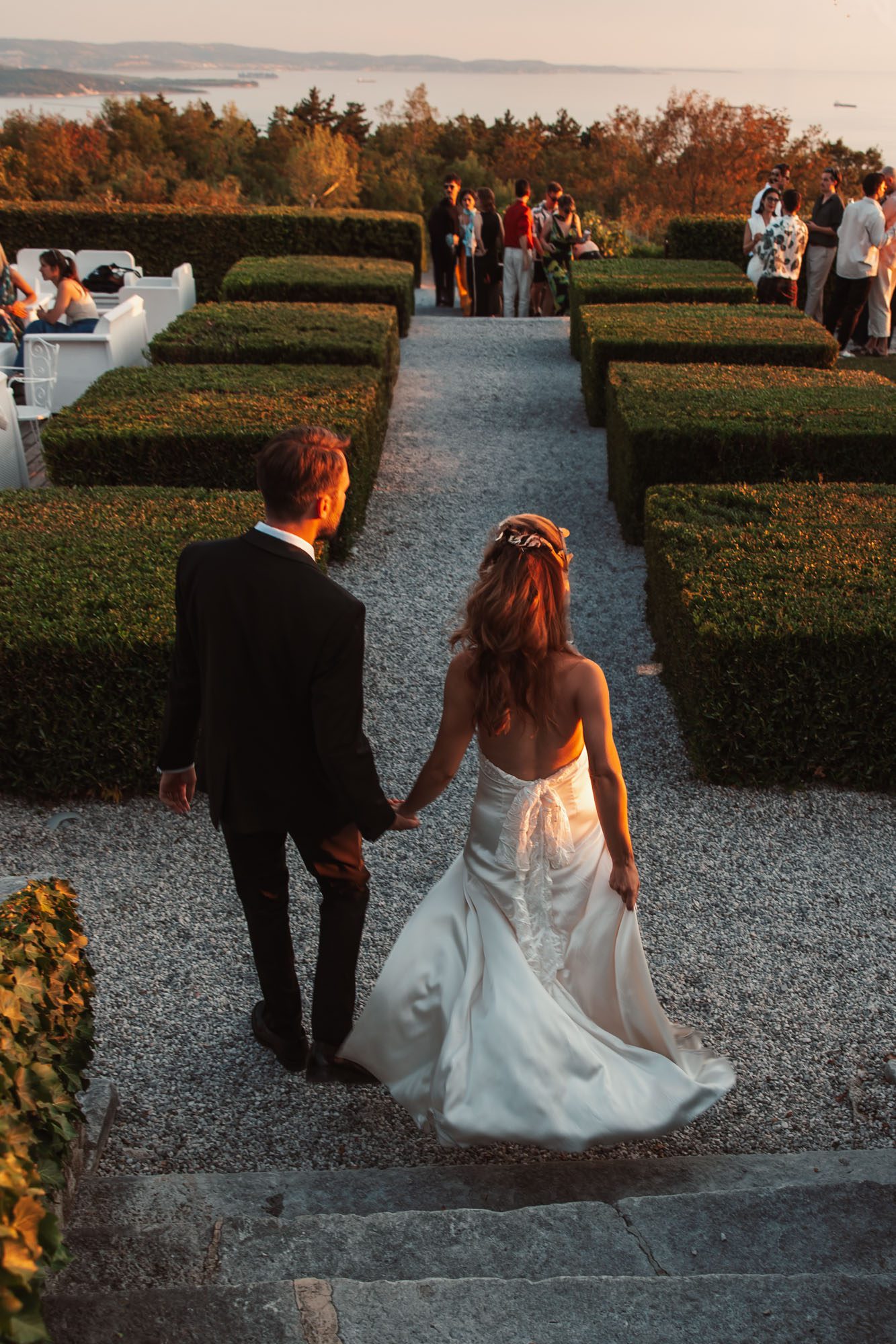 Bride and groom walking through the gardens of Villa Bonomo at sunset overlooking the Adriatic Sea in Trieste Italy