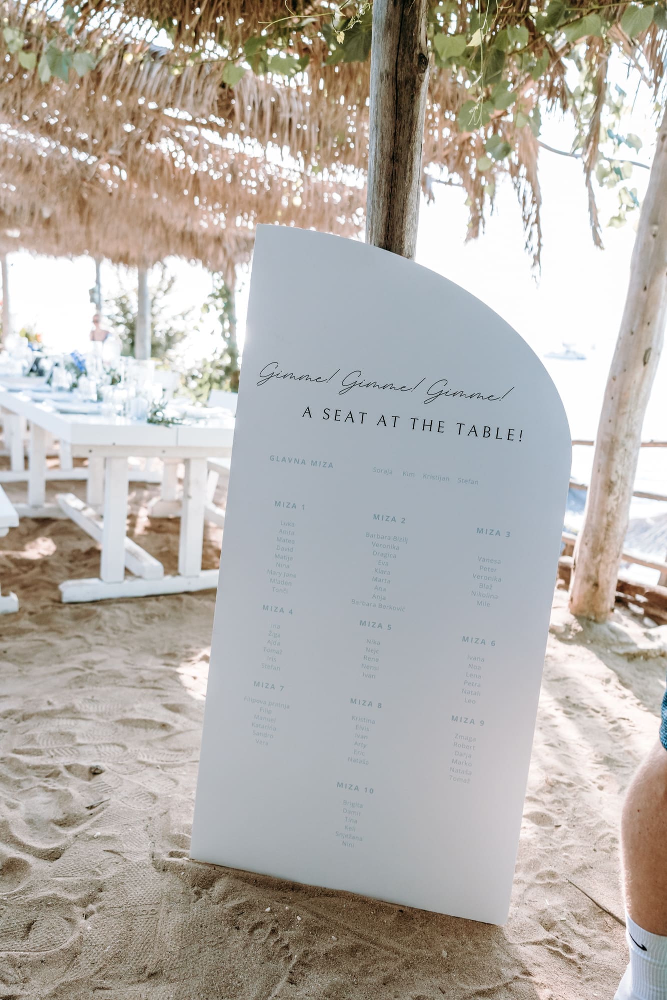 Minimal white wedding seating chart placed in the sand at a beach wedding reception on Levan Island in Croatia.