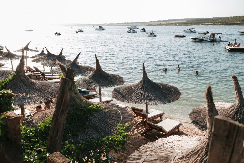 Beach umbrellas and boats along the shoreline of Levan Island in Croatia during a relaxed Adriatic summer wedding celebration.