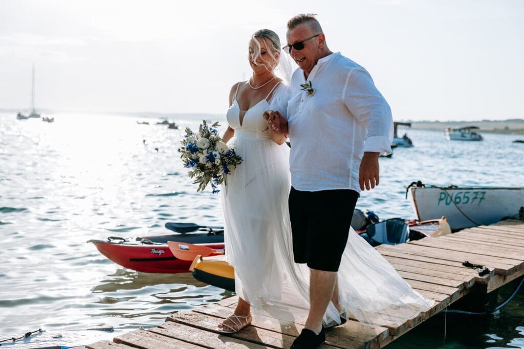 Bride walking with her father along a wooden dock before an intimate beach wedding ceremony on Levan Island in Croatia.
