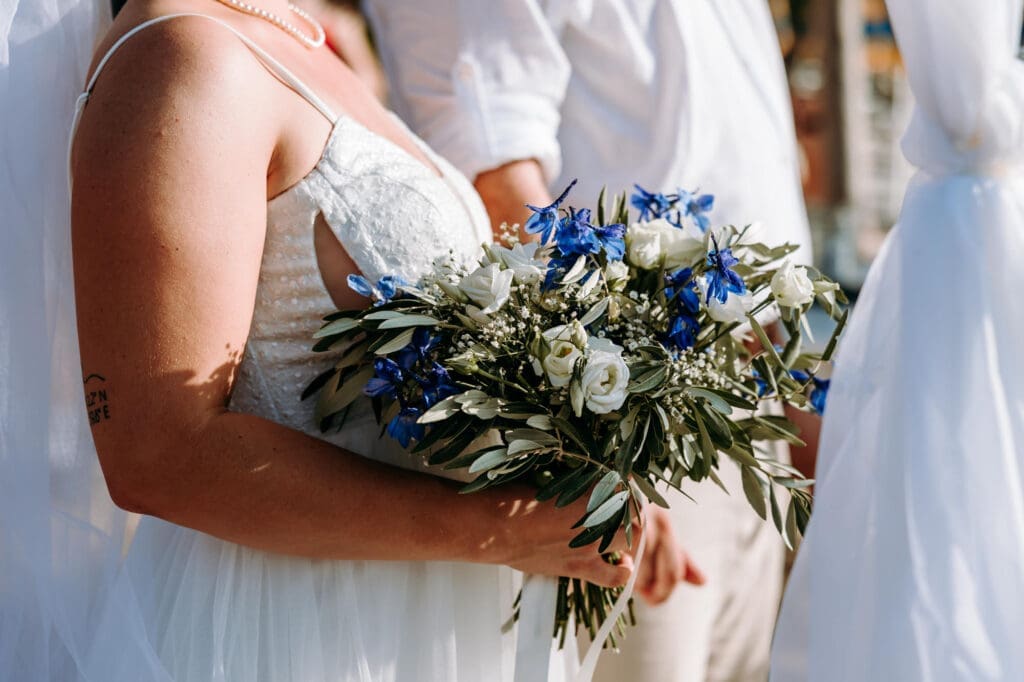 Bride holding a blue and white wedding bouquet during an intimate beach wedding ceremony on Levan Island in Croatia.