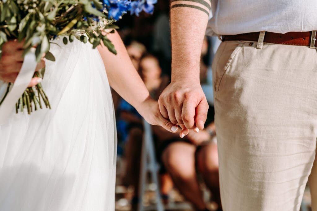 Close-up of the bride and groom holding hands during their beach wedding ceremony on Levan Island in Croatia.