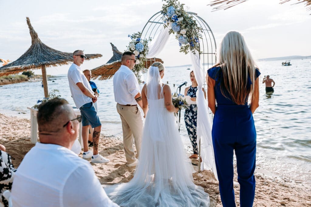 Bride and groom exchanging vows during an intimate beach wedding ceremony beneath a floral arch on Levan Island in Croatia.