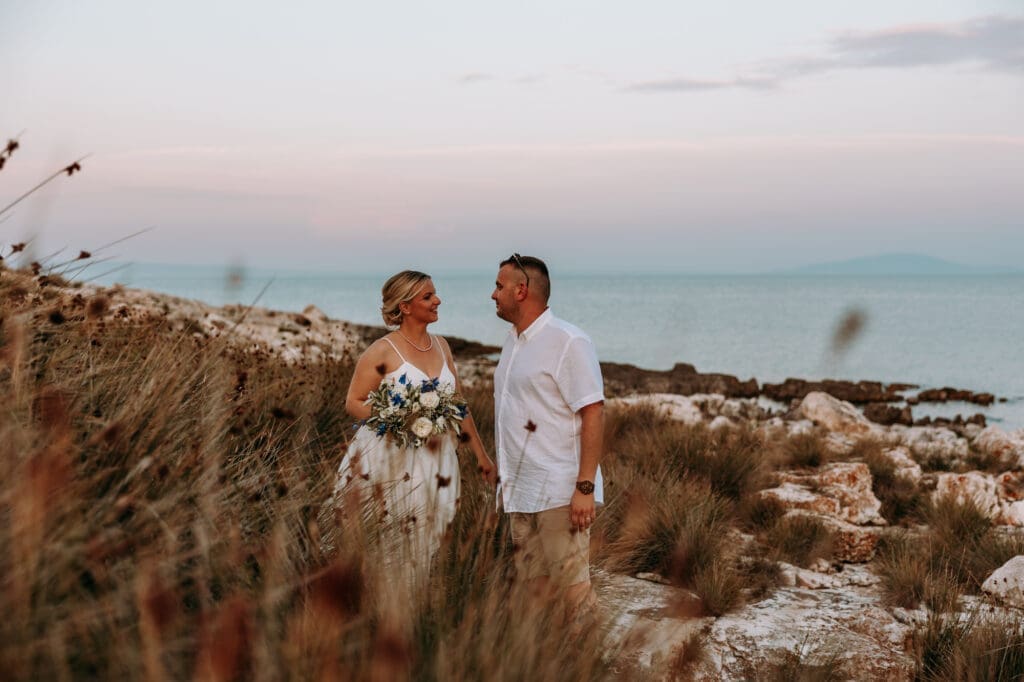 Bride and groom standing together by the Adriatic Sea on Levan Island in Croatia during a romantic sunset portrait session.