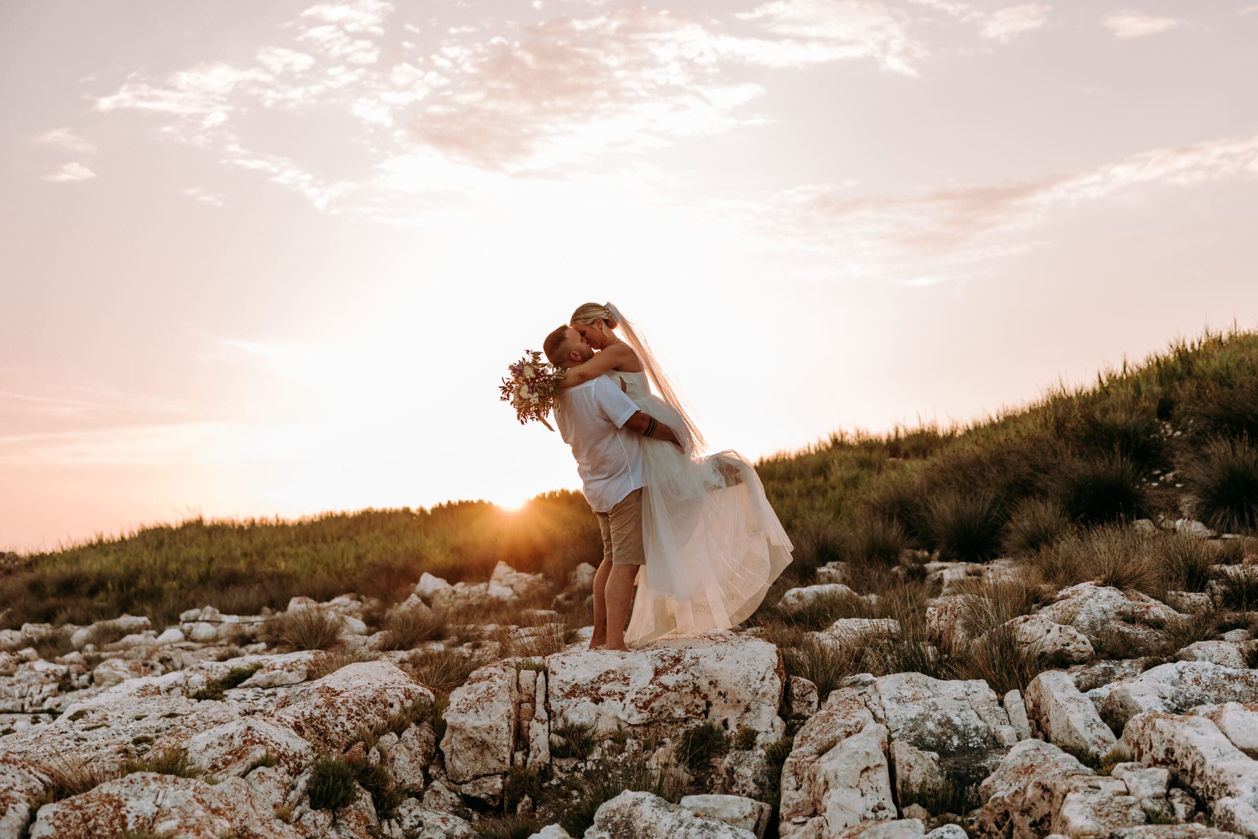 Bride and groom embracing at sunset during a barefoot luxury wedding on Levan Island, Croatia