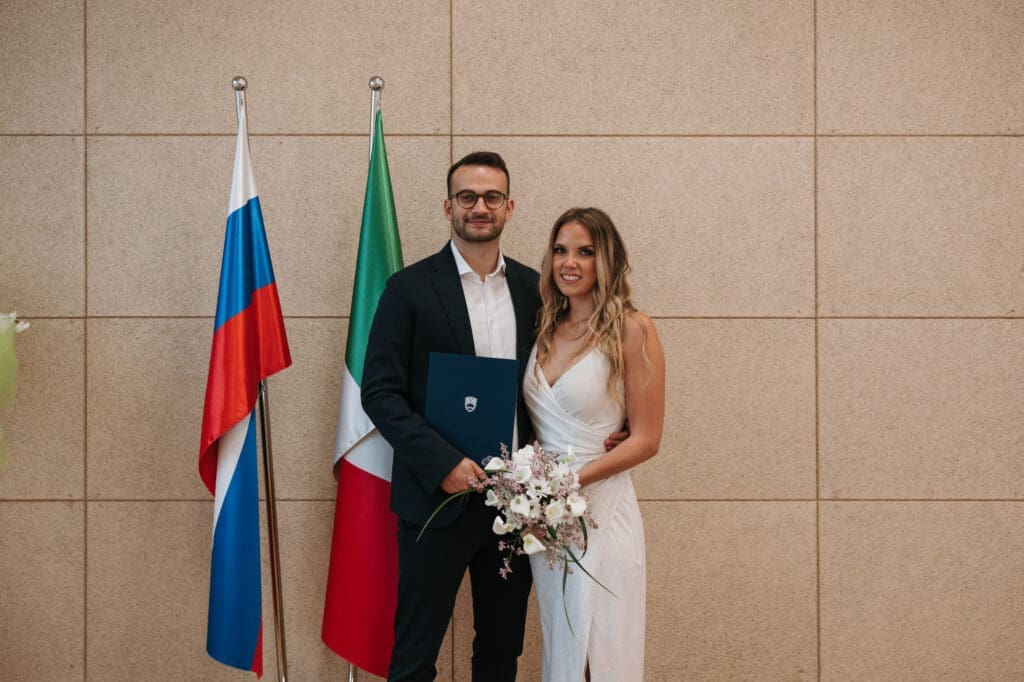 Newlyweds posing with their marriage certificate after a civil wedding ceremony in Koper, Slovenia.