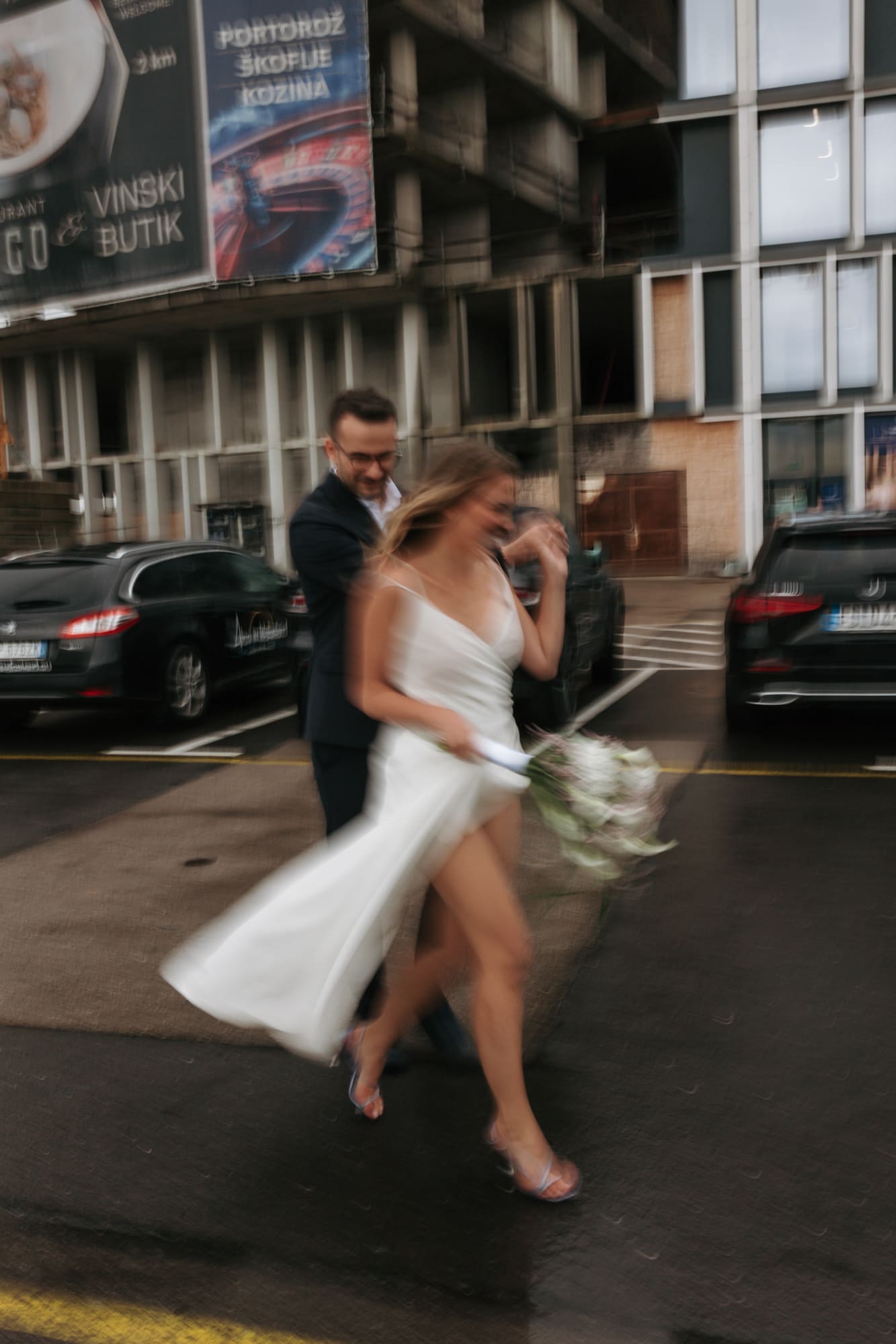Bride and groom hurrying through rainy Koper after their civil wedding ceremony in Slovenia.