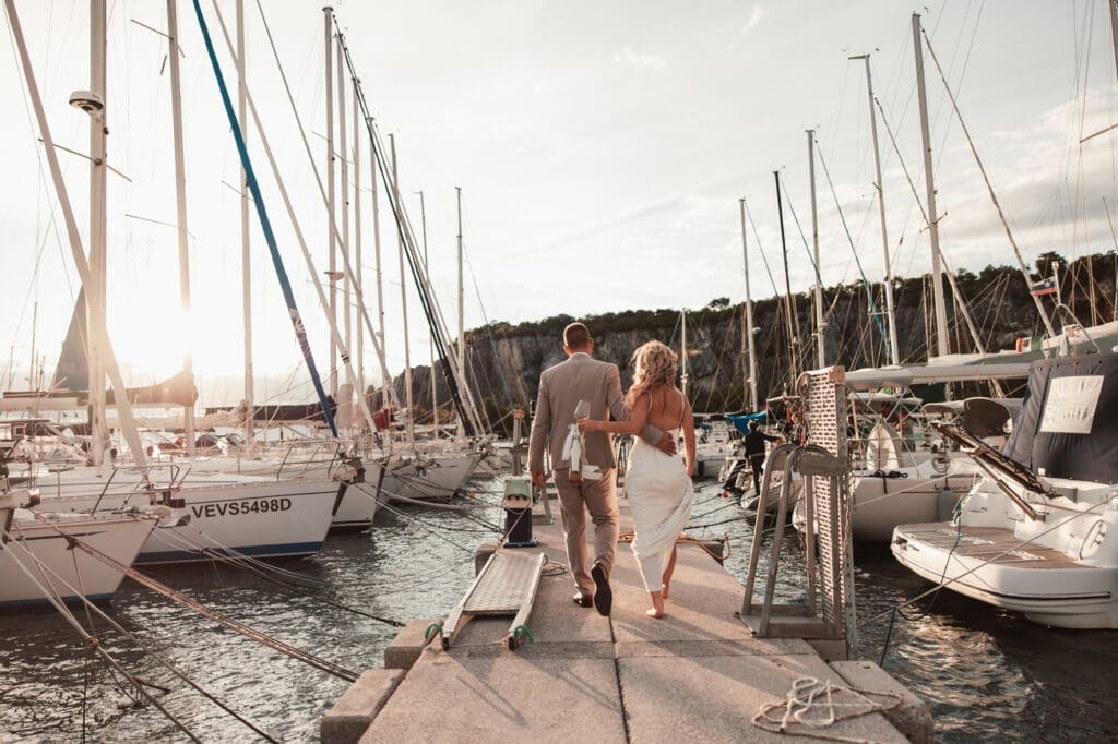 Zala and Matej walking through the marina during romantic wedding portraits in Sistiana near the Adriatic coast in Italy.