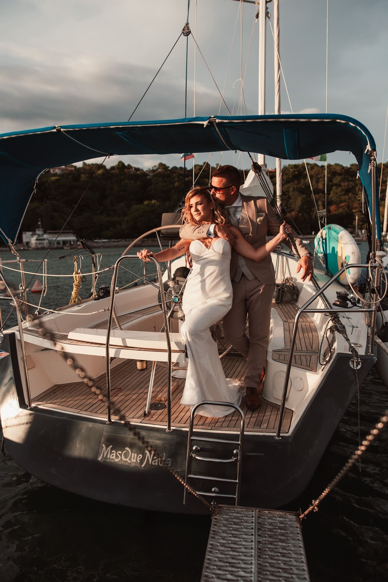 Zala and Matej sharing an intimate moment on a sailboat during wedding portraits in Sistiana, Italy.