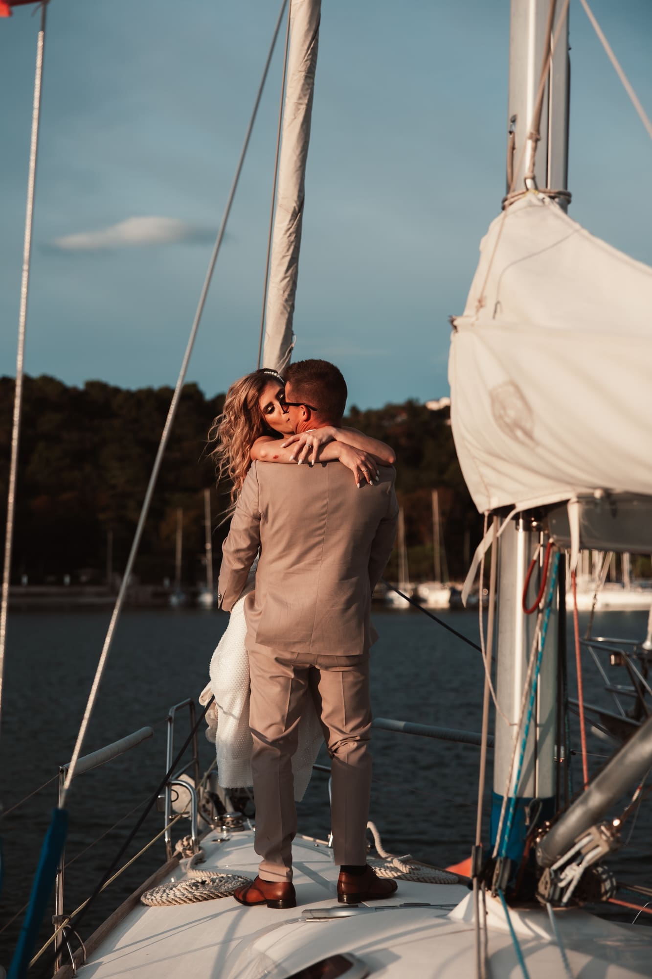 Zala and Matej sharing an intimate moment on Matej's sailboat during wedding portraits in Sistiana on the Adriatic coast.