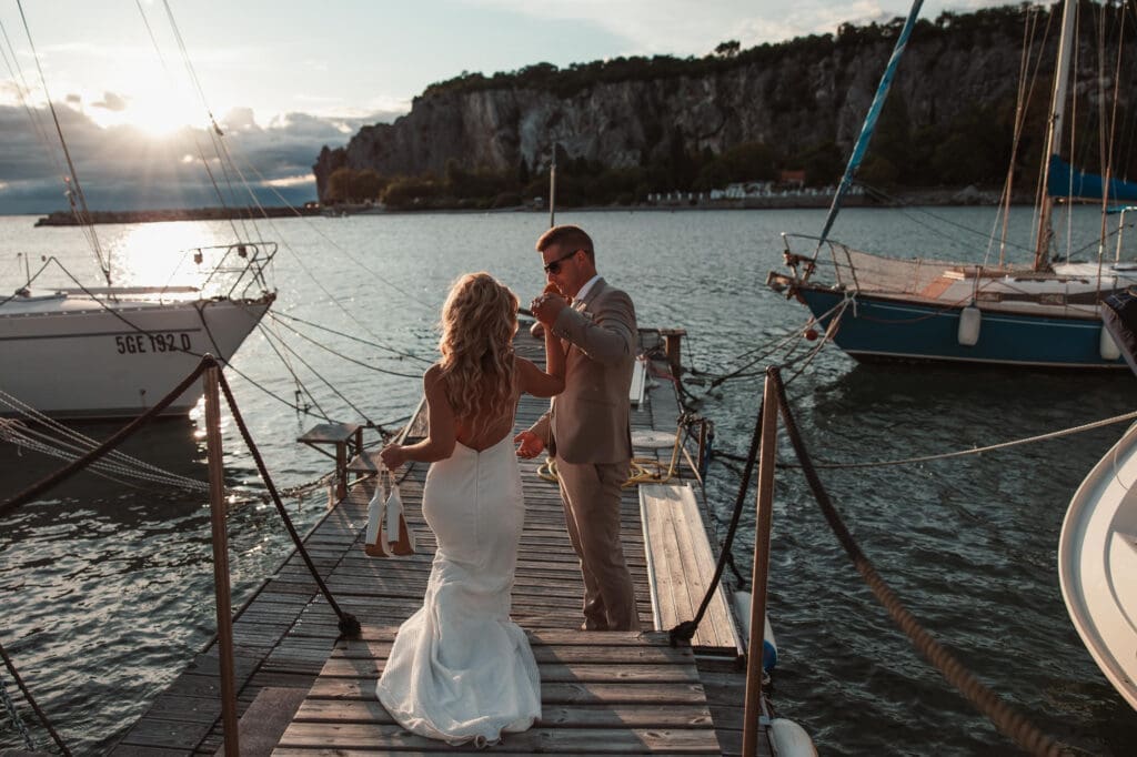 Zala and Matej sharing a joyful moment on the marina dock during romantic wedding portraits in Sistiana on the Adriatic coast.