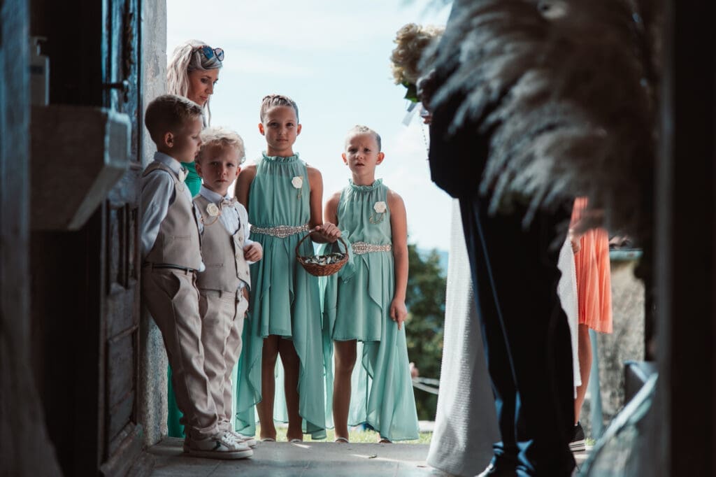 Flower girls and children waiting at the entrance of the Church of St. Michael during Zala and Matej's wedding day.