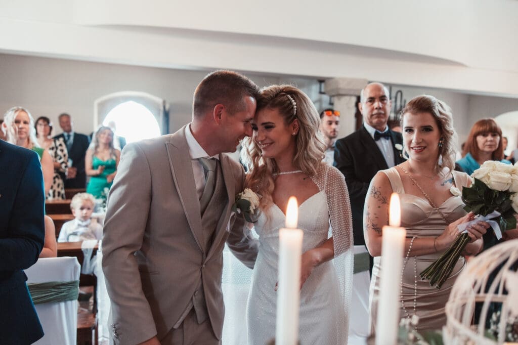 Zala and Matej sharing a joyful moment during their wedding ceremony at the Church of St. Michael in Šmihelj.