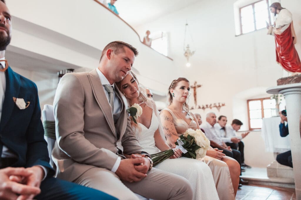 Zala resting her head on Matej's shoulder during their wedding ceremony at the Church of St. Michael in Šmihelj.