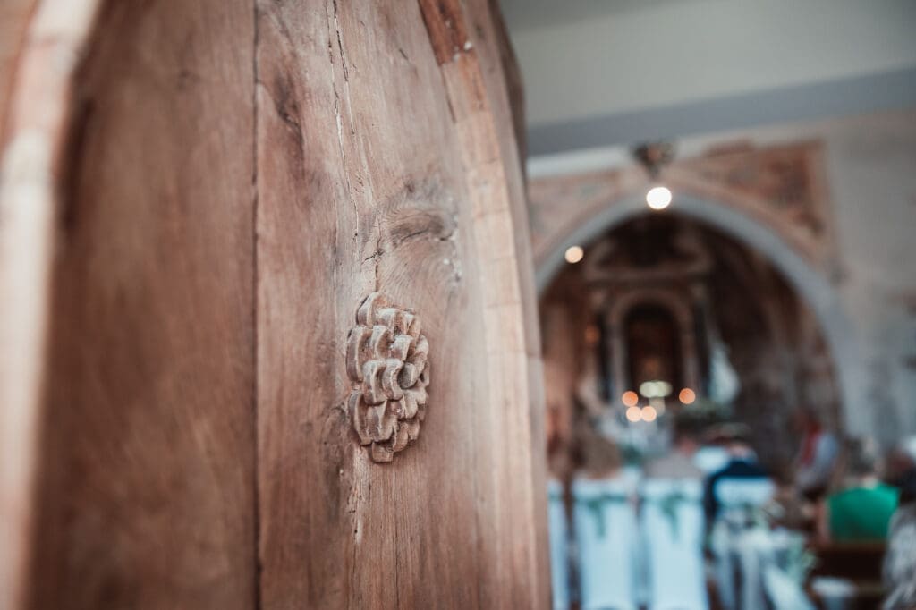 Wooden church door detail inside the Church of St. Michael during Zala and Matej's wedding ceremony in Šmihelj.
