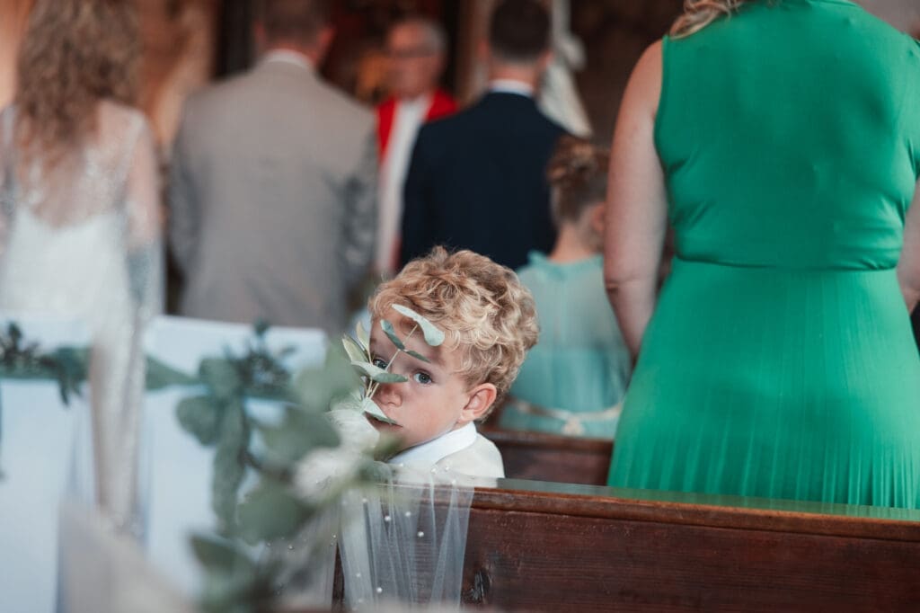 Young wedding guest looking back during Zala and Matej's ceremony at the Church of St. Michael in Šmihelj.