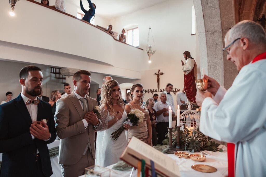 Zala and Matej standing together during their church wedding ceremony at the Church of St. Michael in Šmihelj, Slovenia.