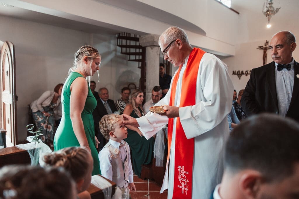 Child receiving a blessing during Zala and Matej's wedding ceremony at the Church of St. Michael in Šmihelj.