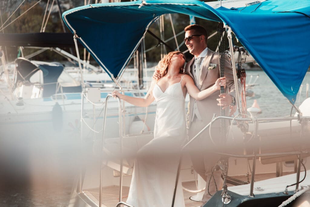 Zala and Matej laughing together on Matej's sailboat during romantic wedding portraits in Sistiana, Italy.