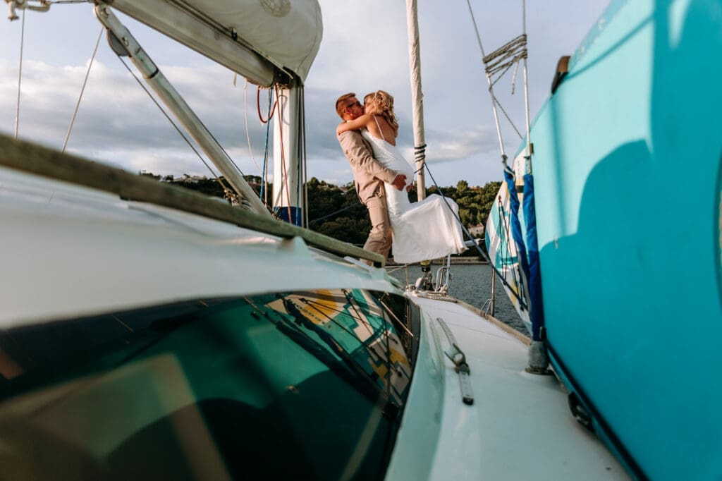 Zala and Matej embracing on Matej's sailboat during romantic wedding portraits in Sistiana on the Adriatic coast.