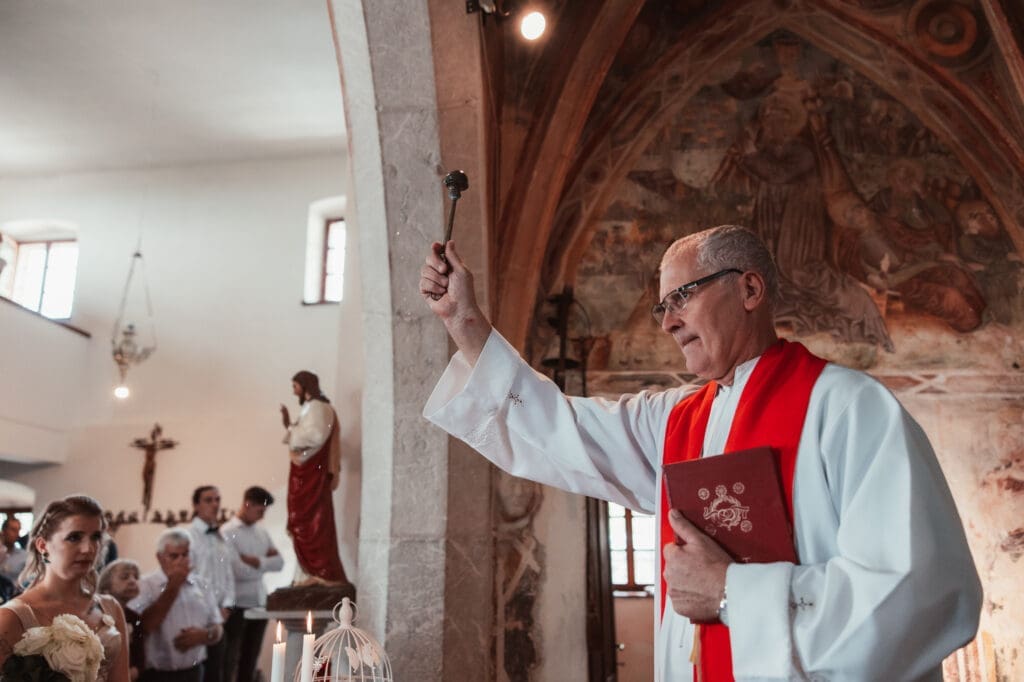 Priest giving a blessing during Zala and Matej's wedding ceremony at the Church of St. Michael in Šmihelj.