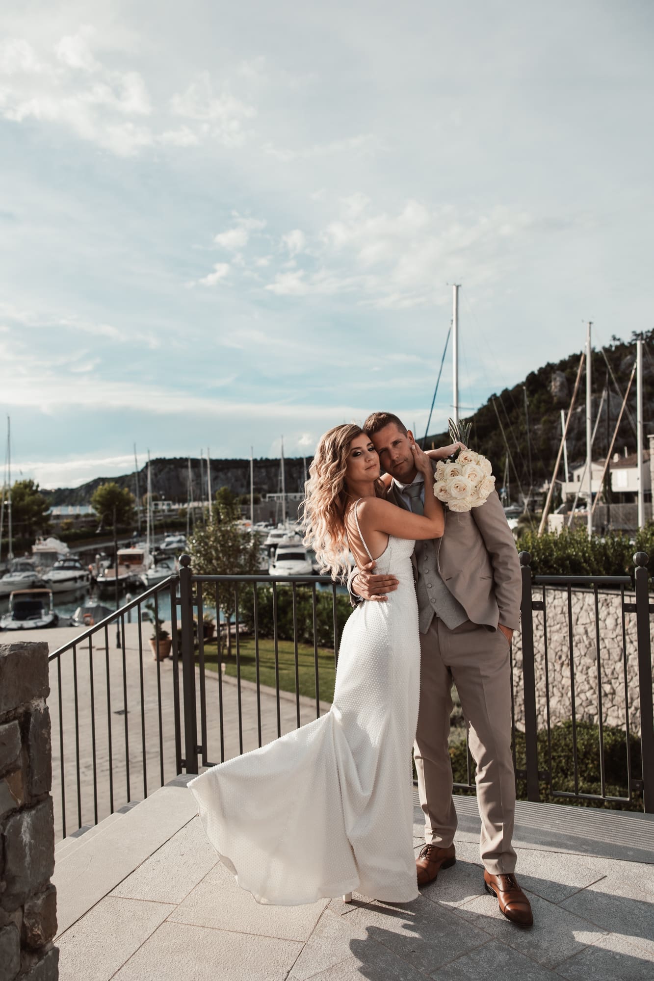 Zala and Matej embracing during wedding portraits in Portopiccolo marina near Sistiana, Italy.