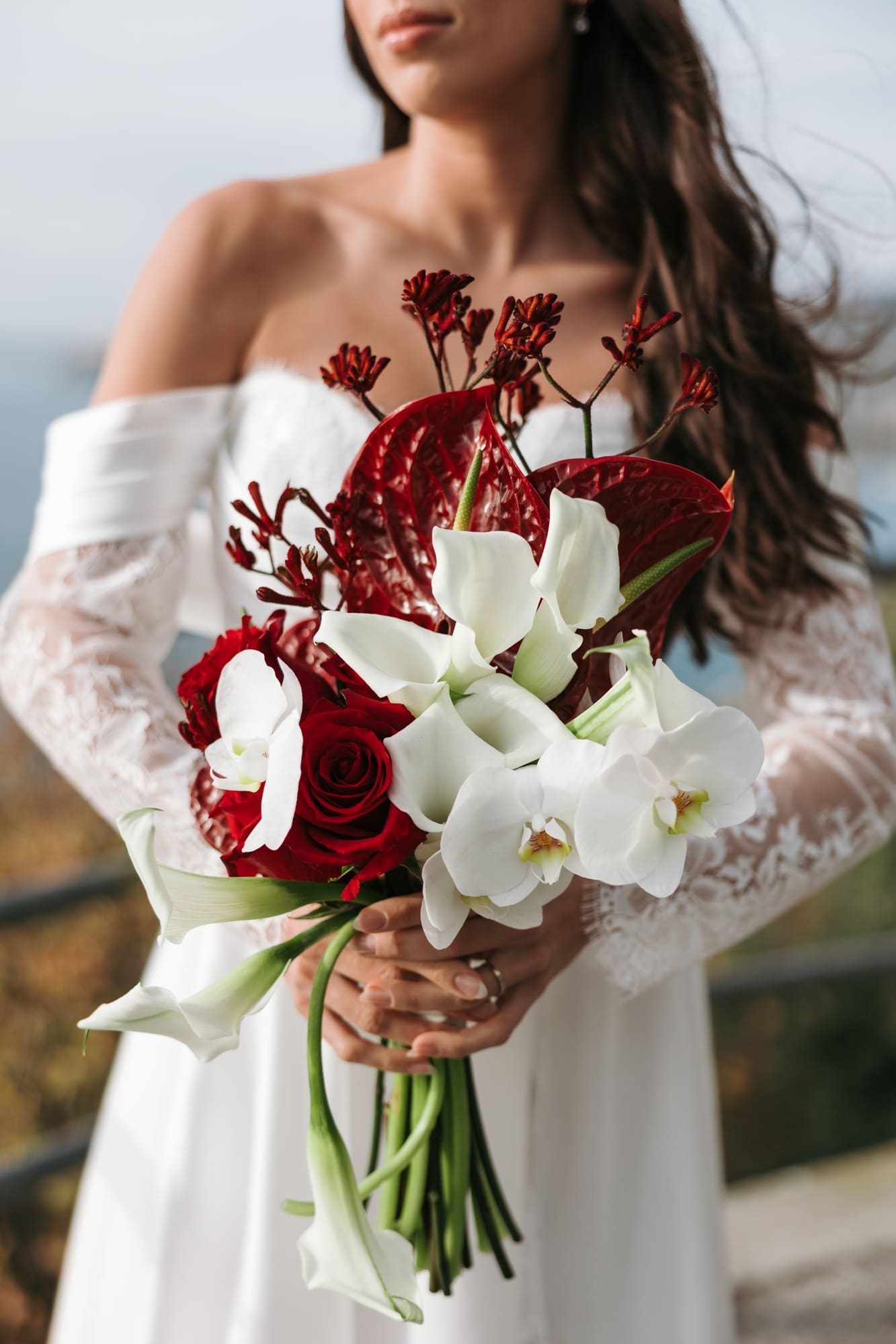 Close-up of an elegant wedding bouquet with white orchids, calla lilies, and red roses during a bridal photoshoot near Trieste, Italy