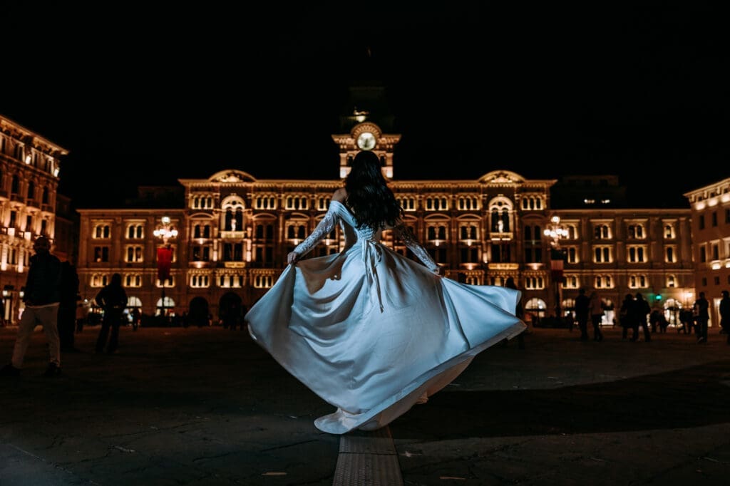 Bride twirling in Piazza Unità d’Italia after dark during a romantic destination wedding photoshoot in Trieste, Italy