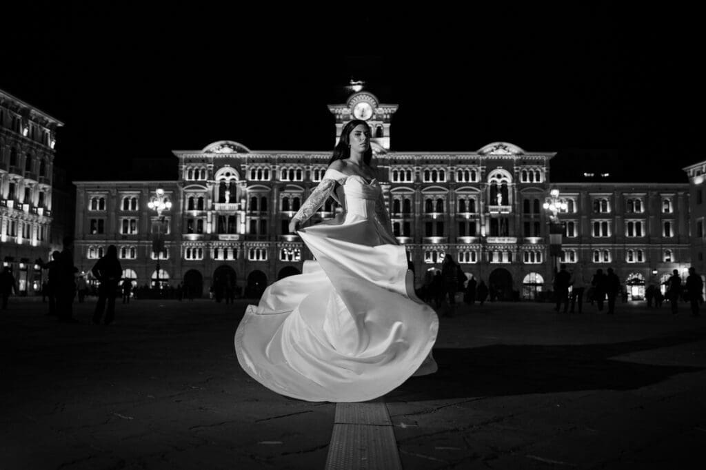 Bride twirling in Piazza Unità d’Italia at night during a black and white wedding photoshoot in Trieste, Italy