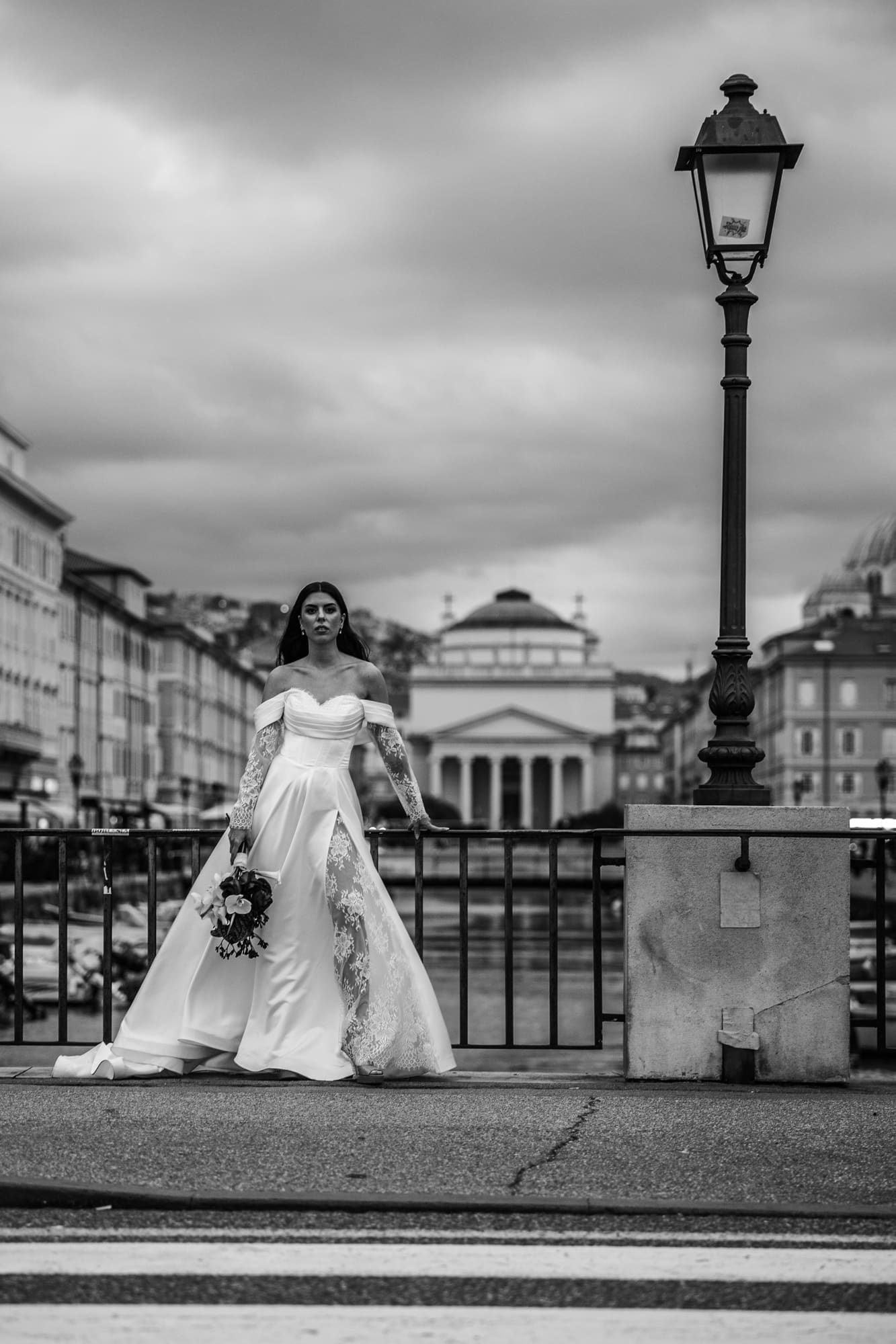 Bride standing on a bridge in Trieste, Italy with Sant'Antonio Nuovo church in the background