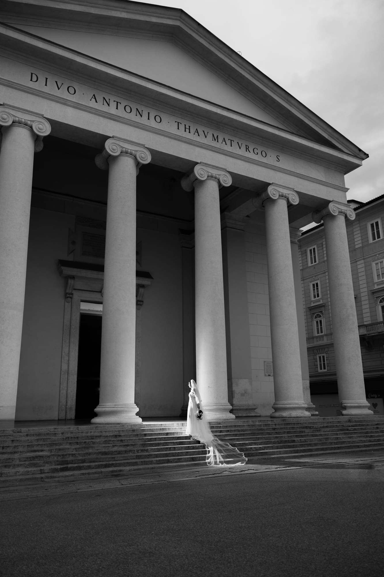 Bride standing on the steps of Sant’Antonio Nuovo beneath its iconic neoclassical columns during a wedding photoshoot in Trieste, Italy
