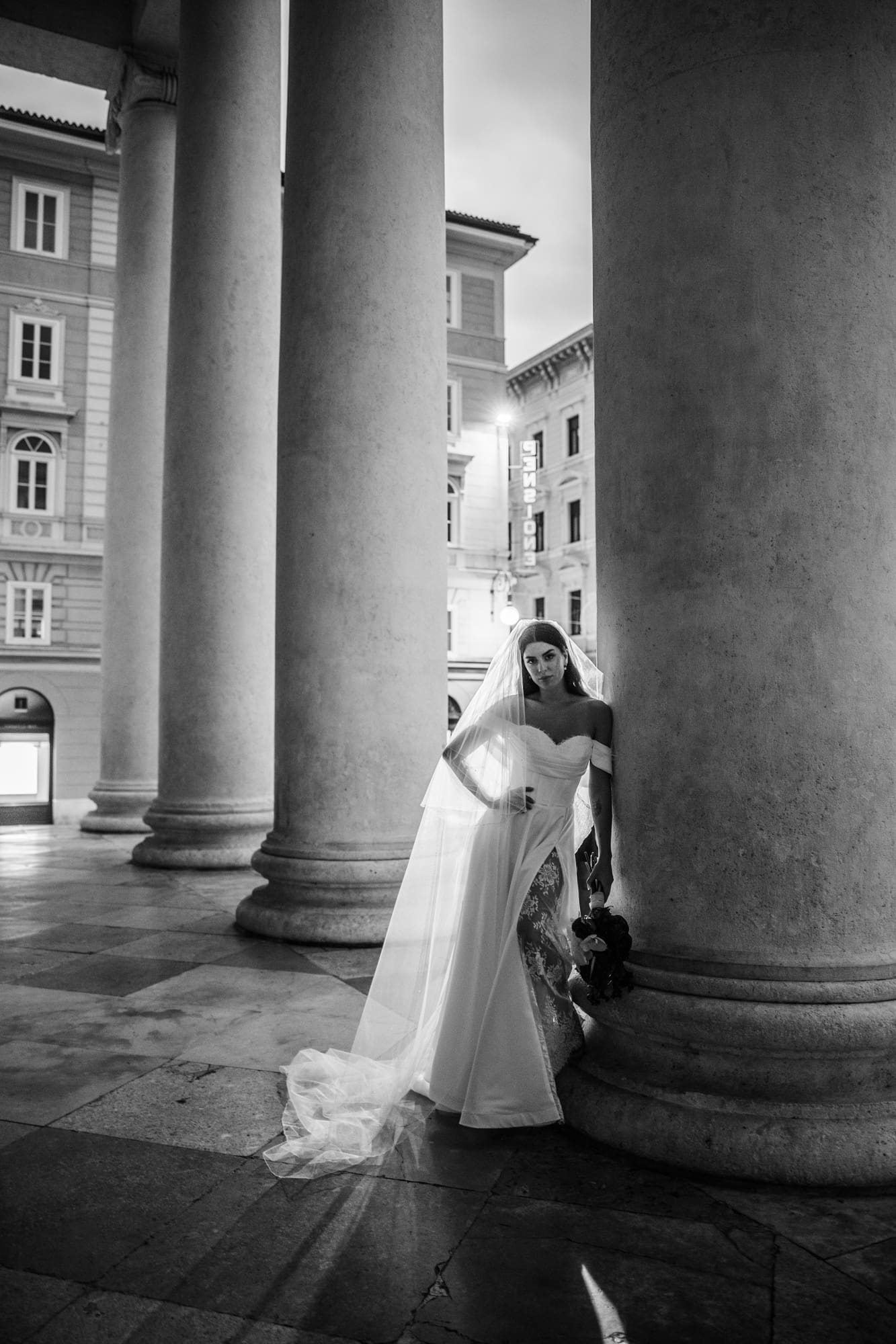 Bride posing beneath the neoclassical columns of Sant’Antonio Nuovo during an elegant wedding photoshoot in the historic center of Trieste, Italy