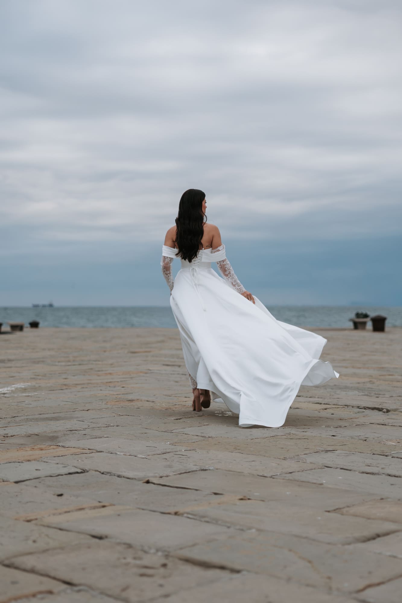 Bride walking along Molo Audace in Trieste, Italy during a romantic waterfront wedding photoshoot
