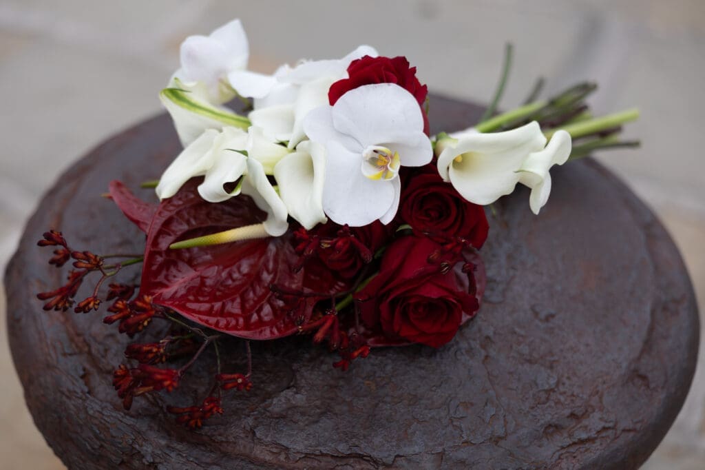 Elegant wedding bouquet featuring white orchids, calla lilies, and deep red roses photographed at Molo Audace in Trieste, Italy