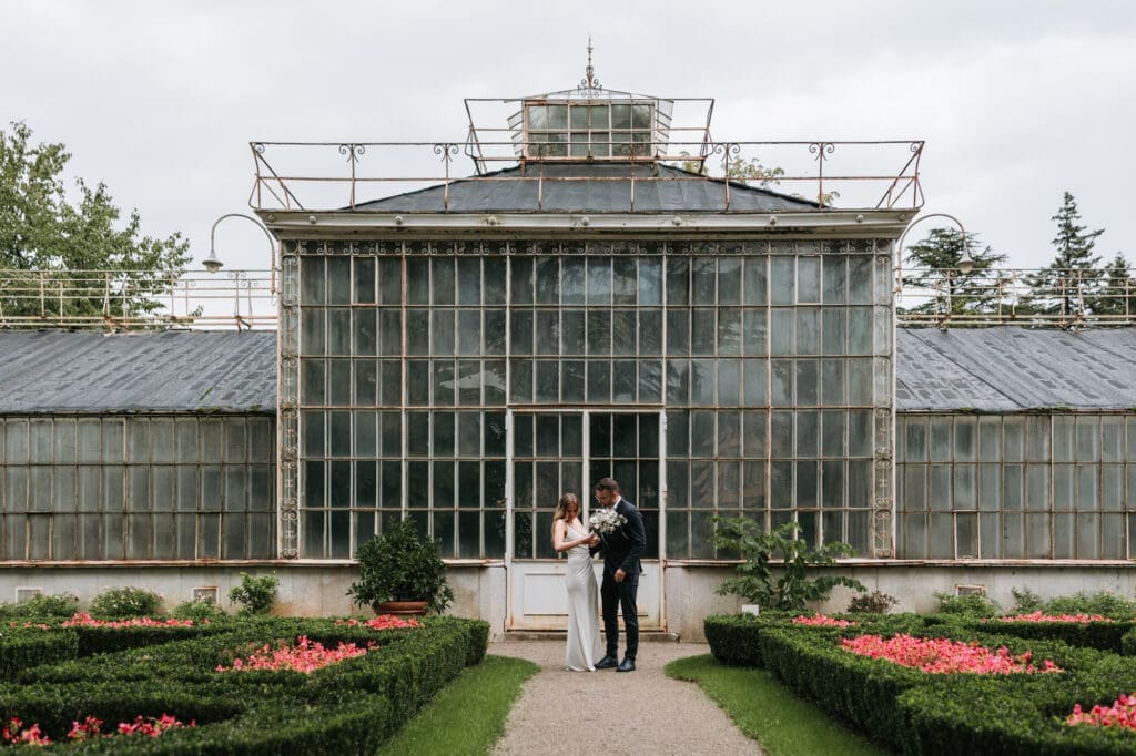 Bride and groom standing in front of the historic greenhouse at Villa Mirasasso near Sežana, Slovenia.