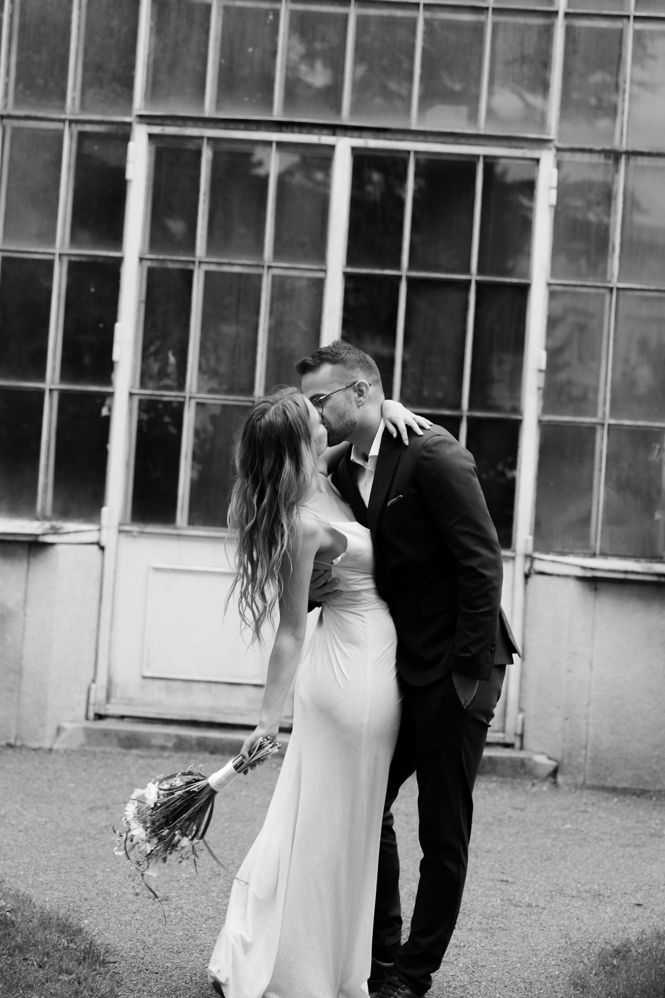 Bride and groom sharing a kiss in front of the historic greenhouse at Villa Mirasasso near Sežana, Slovenia.