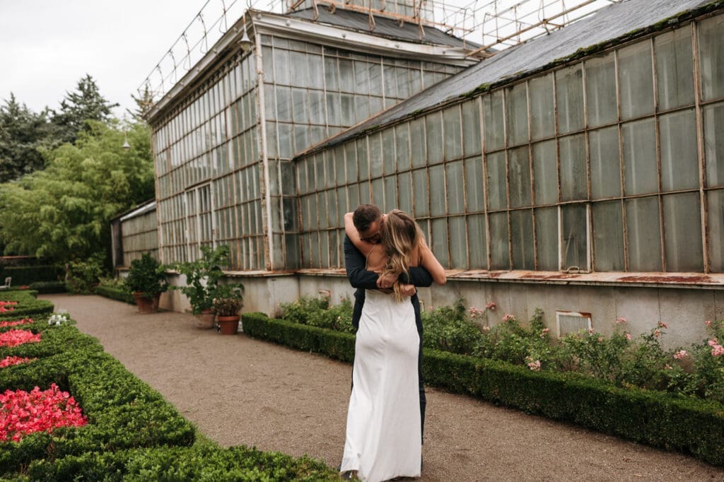 Newlyweds embracing beside the iconic greenhouse at Villa Mirasasso near Sežana, Slovenia.