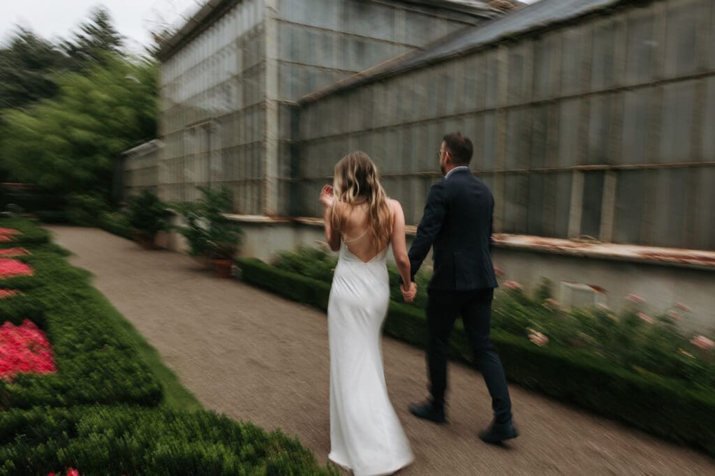 Bride and groom walking beside the historic greenhouse at Villa Mirasasso near Sežana, Slovenia.