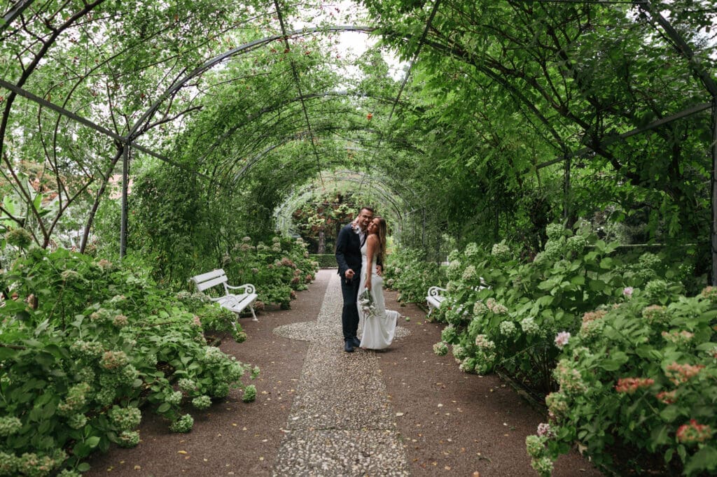Bride and groom walking through a romantic garden tunnel at Villa Mirasasso near Sežana, Slovenia.