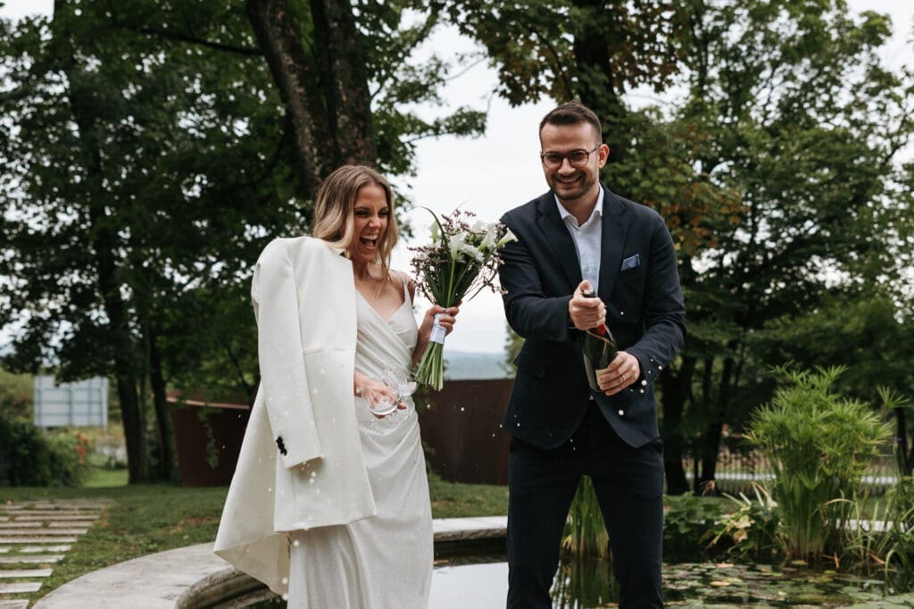 Bride and groom celebrating with champagne in the gardens of Villa Mirasasso during their intimate wedding day in Slovenia.