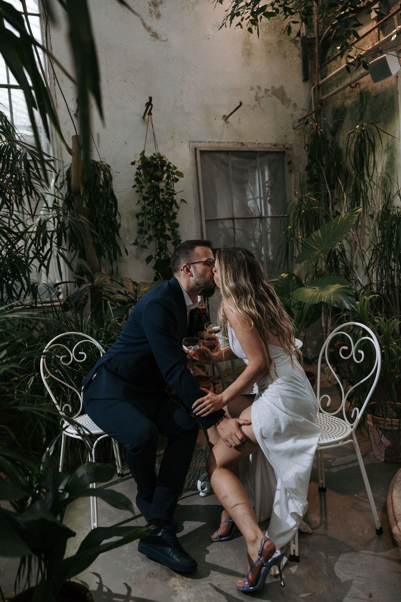 Bride and groom sharing a kiss in the winter garden of Villa Mirasasso surrounded by lush tropical plants.